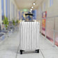 Black and white striped stretch luggage cover with zipper closure protecting a rolling suitcase